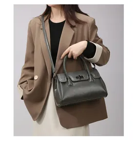 Détail du sac cabas en cuir gris foncé avec poignée tressée et fermoir rotatif en métal