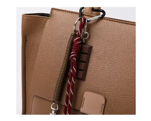 Detail van bruine litchi lederen tas met chocolade hanger en gevlochten touw accessoire