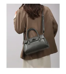 Détail du sac en cuir vert foncé avec poignée tressée et fermoir pivotant métallique