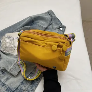 Detail of yellow canvas crossbody bag featuring colorful woven SJCHAO letter strap