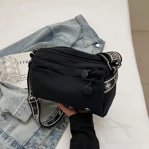 Close-up of black nylon crossbody bag with floral jacquard strap on denim jacket