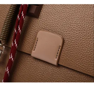 Detailopname van bruin generfd leer met stiksel en decoratief gevlochten touw
