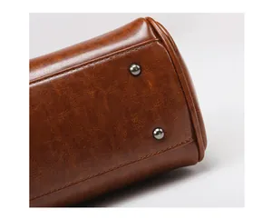 Détail du fond de sac en similicuir marron avec pieds en métal et coutures soignées