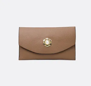 Detail van de karamel lederen envelop clutch met gouden parel gesp en hartvormig detail