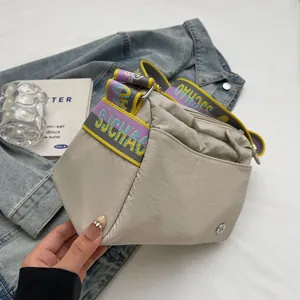 Detail of light beige canvas tote featuring a purple and yellow woven jacquard shoulder strap