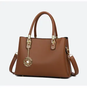 Detail der braunen Handtasche mit Litschi-Muster und goldenem Rosen-Perlen-Anhänger