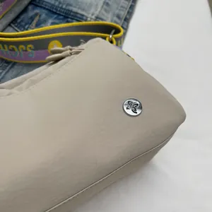 Close-up of beige jacquard canvas texture with silver metal logo and colorful wide strap