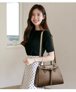 Borsa a mano trapezoidale in pelle marrone con doppi manici e tracolla indossata da modella