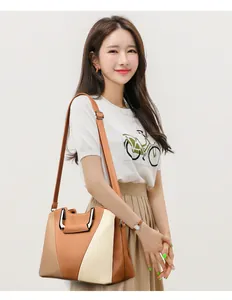 Detail of a large color-block tote bag featuring lychee grain leather and metal top handles