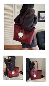 Detail of burgundy leather tote bag with long shoulder straps and white sheep pendant