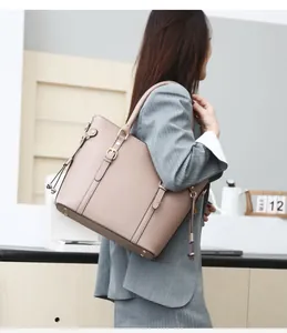 Business style taupe faux leather tote bag with gold buckle detail shown on a model