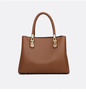 Detail einer braunen Handtasche aus Leder mit Litschimuster und goldenen Schnallen