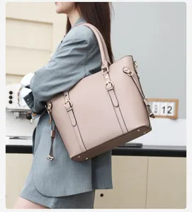 Detailed view of nude leather tote bag with decorative buckles and side drawstrings
