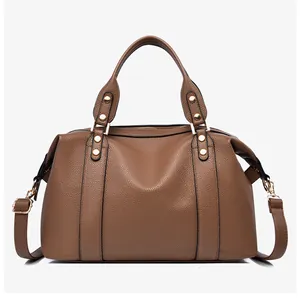 Detail of lychee textured leather Boston bag with golden rivets and brown finish