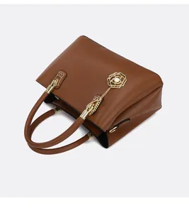 Detail der braunen Lederhandtasche mit goldenen Beschlägen und Rosen-Anhängern