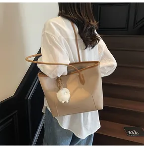 Detail of beige tote bag with brown straps, large capacity, and plush lamb charm accessory