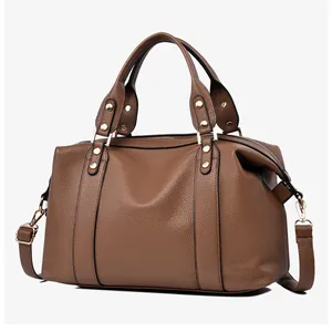 Detailed macro view of the brown litchi grain texture and gold metal hardware on the bag