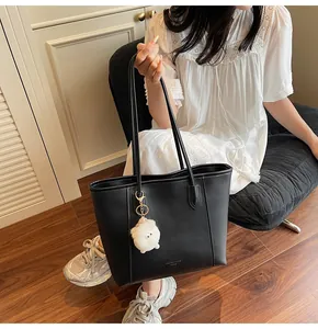 Detailed macro view of black matte leather tote bag with a cute white plush ball keychain