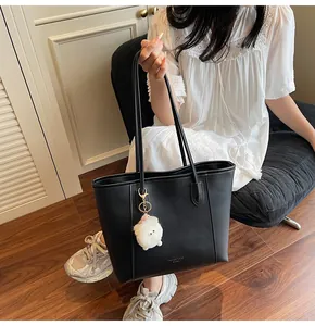 Detail of black PU leather tote bag with gold lettering and cute white plush lamb pendant