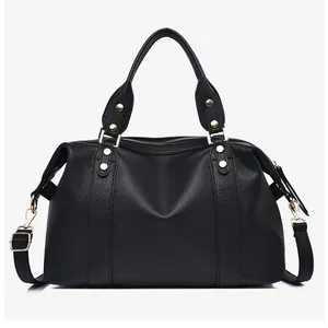 Detail of black lychee grain leather Boston bag with golden rivets and handles