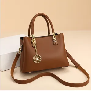Detail der braunen Tasche mit Litschimuster, goldener Rose und Perlenanhänger