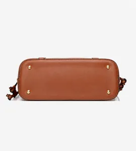 Détail du fond d'un sac en cuir marron avec quatre clous de protection en métal doré