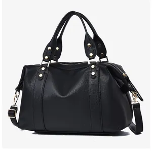 Detail of black lychee grain leather Boston bag with golden hardware and top handles