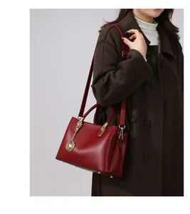 Detailansicht der dunkelroten Ledertasche mit goldenem Rosenanhänger und Umhängeriemen