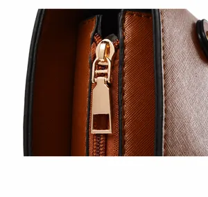 Close-up of golden metal zipper and rectangular puller on brown Saffiano leather bag