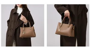 Detail einer braunen Lederhandtasche mit goldenem Rosenanhänger und Metallfüßen zum Schutz