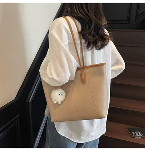 Detail of apricot tote bag with Fashion Trend text and white plush monster keychain
