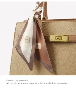 Close-up of khaki pebbled leather handbag with gold twist lock and decorative silk scarf