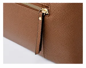 Detail of high-quality golden metal zipper on brown litchi pattern leather boston bag