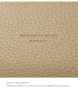 Macro detail of beige lychee grain leather featuring embossed AIBEINI brand logo