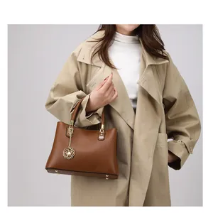 Detail einer dunkelbraunen Lederhandtasche mit goldenem Blumenanhänger und Beschlägen