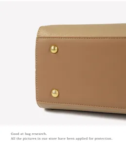 Macro detail of beige pebble leather stitching and golden metal protective bag feet