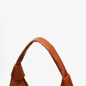 Close-up of woven leather texture and soft handle detail on brown tote bag