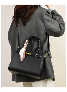 Close-up of a black pebbled leather tote bag with gold lock and floral silk scarf detail