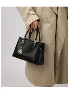 Detail einer schwarzen Handtasche aus Narbenleder mit goldener Blume am Model