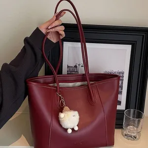 Large burgundy leather tote bag with long straps and cute white plush charm for women