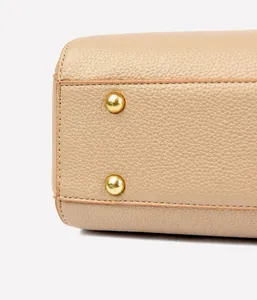 Macro detail of the pebbled leather texture and gold protective studs on the tote bag base