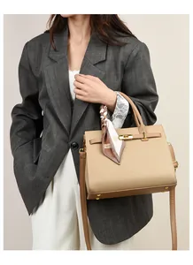 Business style camel handbag with silk scarf detail worn by a model in a grey suit