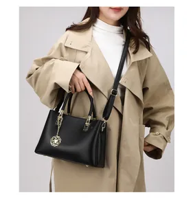 Nahaufnahme der schwarzen Handtasche mit Litschi-Muster, Goldbeschlägen und Rosenanhänger