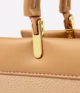 Macro shot of khaki leather tote bag featuring gold hardware and premium stitching