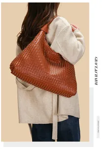 Dettaglio borsa hobo a spalla in pelle intrecciata caramello con cappotto
