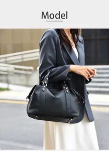 Close-up of black lychee grain leather Boston bag with golden rivets in a street setting