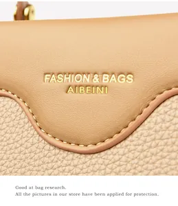 Detail of lychee pattern leather and gold logo on a stylish beige tote handbag