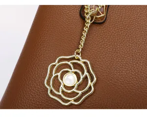 Detail aus braunem Leder mit Lychee-Muster, Goldkette und Perlen-Kamillen-Anhänger