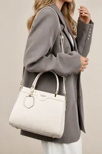Detail of cream white pebbled leather tote bag with gold hardware and fashion text