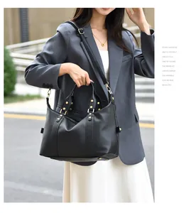 Close-up of black lychee grain leather Boston bag with gold rivets and detachable strap